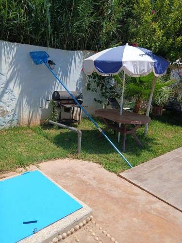 a blue and white umbrella next to a chair and a table at Kariat arkma in Nador