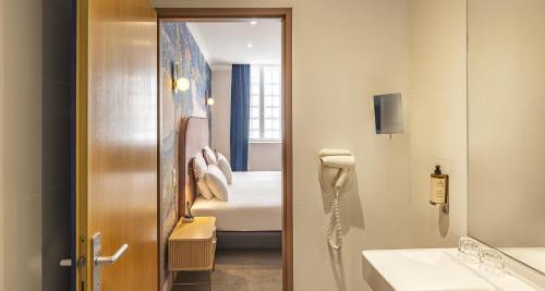 a hotel room with a bathroom with a bed and a sink at Best Western Poitiers Centre Le Grand Hôtel in Poitiers