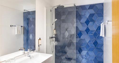 a bathroom with a shower with blue tiles at Best Western Poitiers Centre Le Grand Hôtel in Poitiers