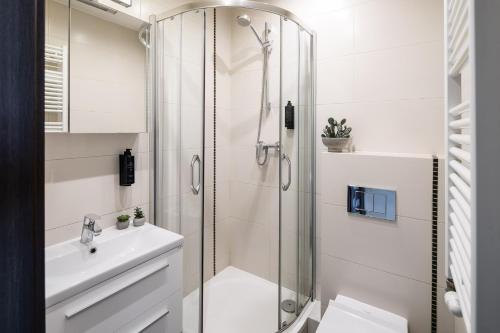 a white bathroom with a shower and a sink at Wavelo Apartments in Kraków