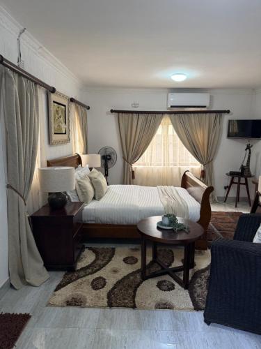 a bedroom with a bed and a table and a couch at The Java Tree Suite in Lusaka