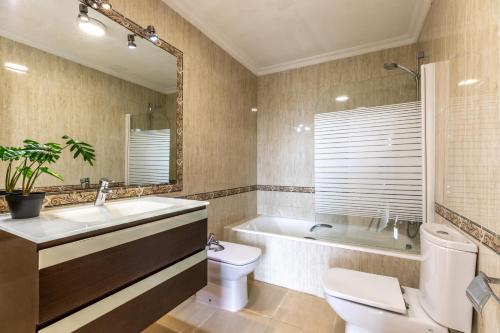 a bathroom with a toilet and a tub and a sink at Spacious villa for 10 with private pool in El Port