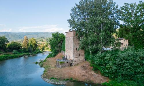 an old castle on the side of a river at Tuscany Tower Villa in Capolona