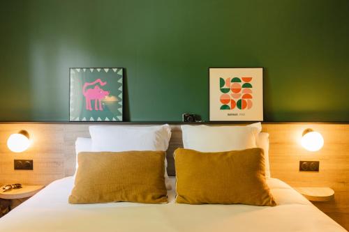 a bed with two pillows and a green wall at Sure Hotel by Best Western Tours Sud in Chambray-lès-Tours