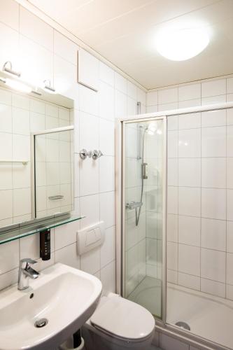 a bathroom with a sink and a shower and a toilet at NECKARWESTHEIMER Hotel in Neckarwestheim