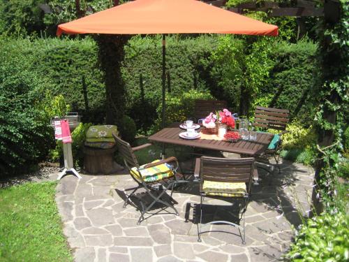 a table and chairs with an orange umbrella at Ferienwohnung am Wäldchen in Kurort Gohrisch