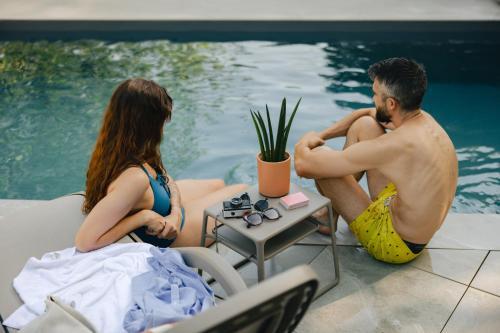 a man and a woman sitting next to a swimming pool at Sure Hotel by Best Western Tours Sud in Chambray-lès-Tours