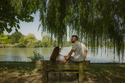 a man and woman sitting on a bench in front of a lake at Sure Hotel by Best Western Tours Sud in Chambray-lès-Tours