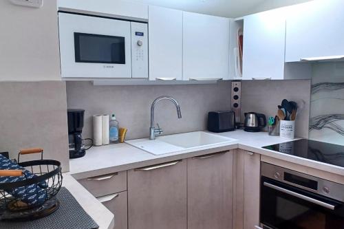 een keuken met witte kasten en een spoelbak bij Nice apartment with pool - near the beach in Bandol