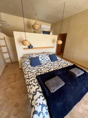 a bedroom with a large bed with blue pillows at Villa'S in Zaouiet Bouzarktoune