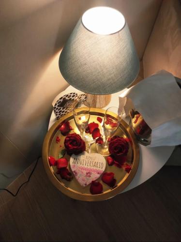 a table with a plate with wine glasses and roses at Domus Cuomo B&B in Nocera Inferiore