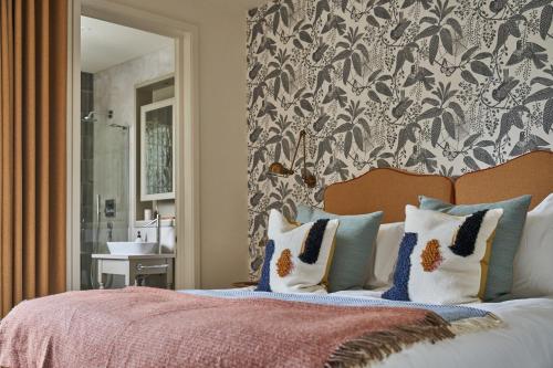 a bedroom with a bed with pillows and a wall at The Lakes By YOO in Lechlade