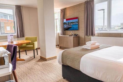 a hotel room with a bed and a desk and a table at Copthorne Hotel Plymouth in Plymouth