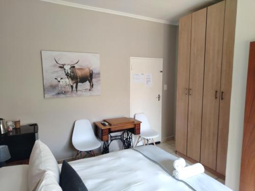 a bedroom with a bed and a desk with a cow on the wall at Novalia in Colesberg