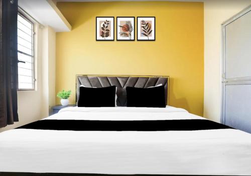a bedroom with a large white bed with three pictures on the wall at The Vinayaka Guest House in Dānāpur