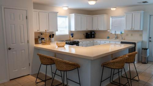 a kitchen with white cabinets and a island with bar stools at Tranquil Turquoise Retreat home in South Padre Island