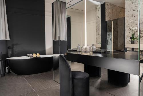 a bathroom with a tub and a black table and chair at Casa Guttmann in Rome
