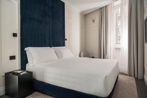 a bedroom with a white bed and a blue wall at Casa Guttmann in Rome