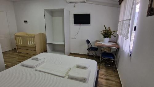 a room with a bed and a table and a television at Vila Luen in Berat
