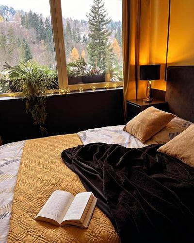 Una cama con dos libros y una ventana. en Dom i Las, en Brenna