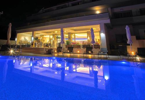 a swimming pool at night with chairs and umbrellas at The Dome Luxury in Limenaria