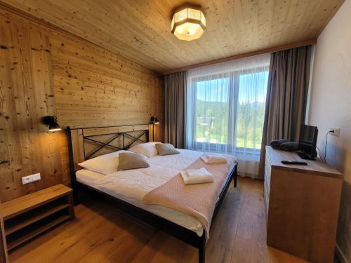 a bedroom with a large bed in a wooden wall at ALPIN 7 Jasná - Free Jacuzzi & Sauna in Demanovska Dolina