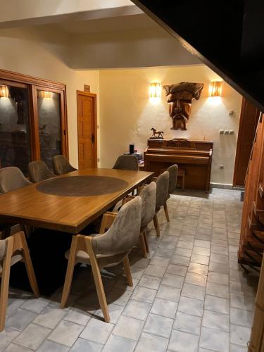 a dining room with a table and a piano at Villa'S in Zaouiet Bouzarktoune
