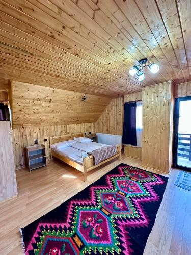 a bedroom with a bed in a wooden room with a rug at Pensiunea Casa Petran in Breb