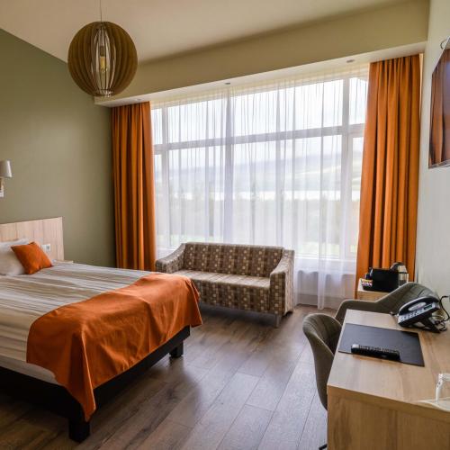 a bedroom with a bed and a couch and a window at Hotel Hallormsstadur in Hallormsstaður