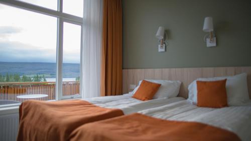 a bedroom with two beds and a large window at Hotel Hallormsstadur in Hallormsstaður