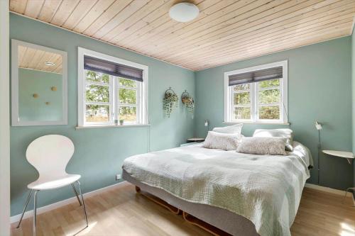 a blue bedroom with a bed and two windows at 2730-Nexo-Ostre-Strandvej-22 in Dueodde