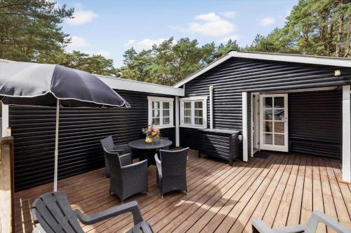 a deck with a table and chairs and an umbrella at 2730-Nexo-Ostre-Strandvej-22 in Dueodde