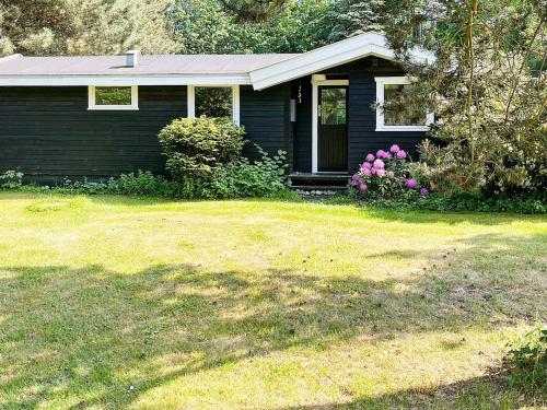 a small blue house with flowers in the yard at 6 person holiday home in Gilleleje-By Traum in Gilleleje