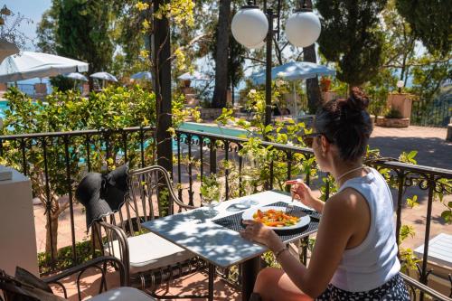 a woman sitting at a table with a plate of food at Excelsior Palace Hotel in Taormina