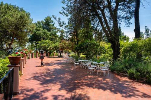 a person walking down a sidewalk with tables and chairs at Excelsior Palace Hotel in Taormina