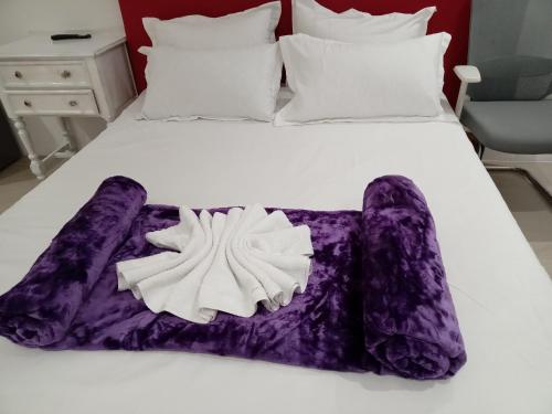 a white bed with purple sheets and pillows at Jorash Guesthouse in Cape Town