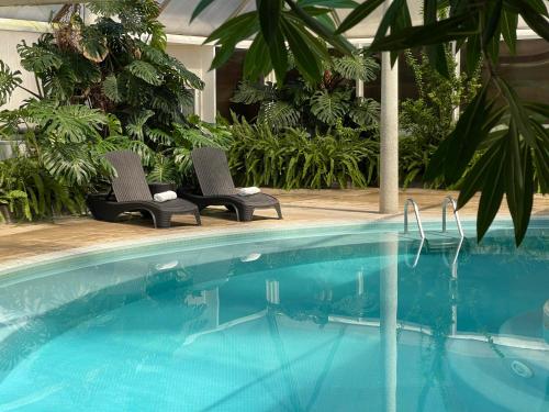 two chairs sitting next to a swimming pool at QH Praia de Quiaios in Praia de Quiaios