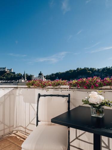 a table and a chair on a balcony with flowers at Hotel Sacher Salzburg in Salzburg