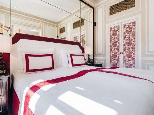 a bedroom with a large bed with red and white pillows at Hotel Sacher Salzburg in Salzburg