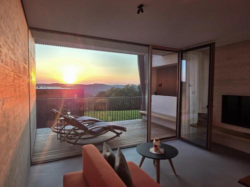 a living room with a balcony with a sunset view at Stock & Stein Lodges in Bad Gleichenberg