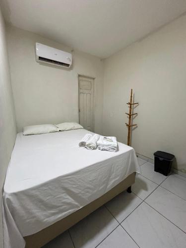 a bedroom with a bed with white sheets and a air conditioner at Pousada Cactus in Barreirinhas