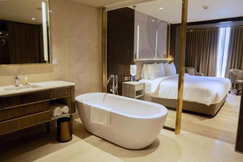 a bathroom with a bath tub and a bed at Merlis Hotel Coimbatore in Coimbatore