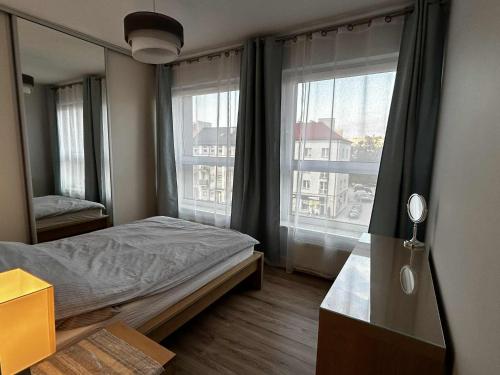 a bedroom with a bed and a large window at Apartament Wygodny 2 in Białystok