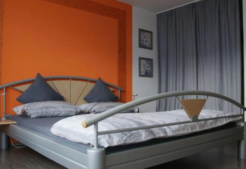 a bed with blue pillows and an orange wall at Ferienwohnung Allgäu-Harmonie - Pool, Sauna, Bergblick, 2 Zimmer in Scheidegg