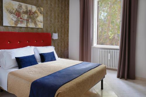 1 dormitorio con 1 cama con cabecero rojo y ventana en Domus Chiara al Colosseo, en Roma