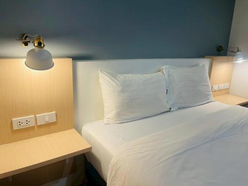 a bedroom with a bed with a white pillow and a lamp at Shade House - Bitec Bangna in Bangkok