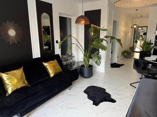 sala de estar con sofá negro y almohadas de oro en Apartament Nowość 65 m2, 