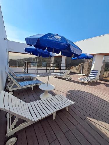 a deck with chairs and a table and an umbrella at Flat Golden Beach in Guarujá