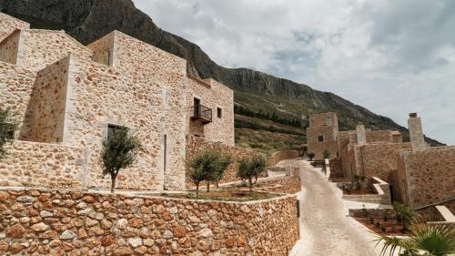 a stone building with a mountain in the background at Anemos Suites Mani 