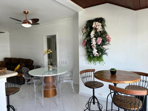 a living room with a table and chairs and flowers on the wall at Flat Golden Beach in Guarujá
